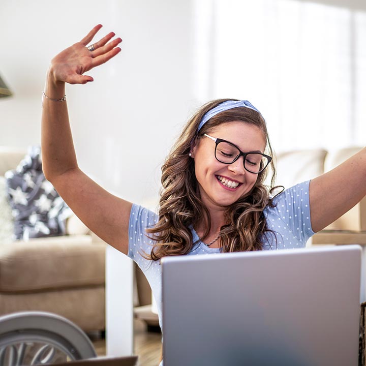 A lady celebrating good news on a laptop computer
