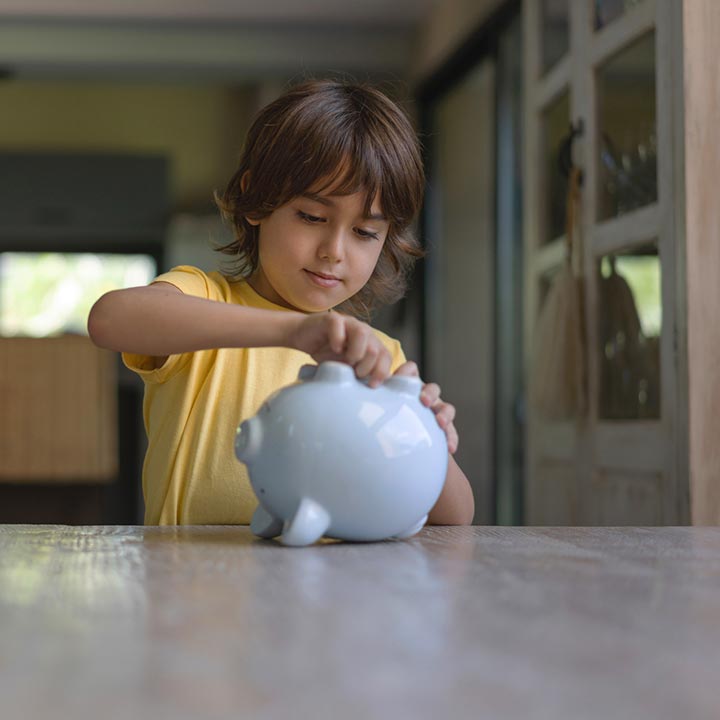 Little boy getting into his piggy bank